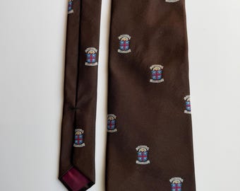Könnte beinhalten: Eine braune Krawatte mit einem sich wiederholenden Muster aus kleinen Wappen. Jedes Wappen zeigt ein rotes Kreuz auf blauem Grund, gekrönt von einer Krone und dem Text "JERUSALEM" und "ORDER OF THE HOLY SEPULCHRE" in kleiner weißer Schrift.