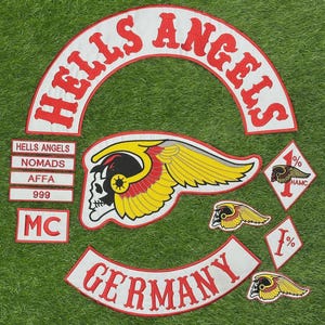 Puede incluir: Una colección de parches bordados que incluye un arco blanco grande con texto rojo que dice HELLS ANGELS, un emblema central de calavera alada, un arco blanco con texto rojo que dice GERMANY y parches más pequeños con texto como NOMADS, AFFA, 999, MC y 1%.