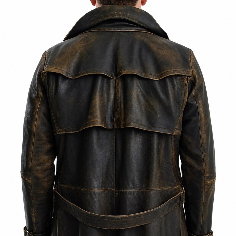 May include: A dark brown leather trench coat featuring a distressed finish, a wide collar, a back storm flap, and a matching belt at the waist. The coat displays visible stitching details and a weathered texture across the entire surface.