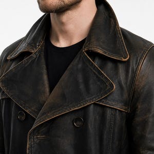 May include: A dark brown, distressed leather double-breasted coat featuring a wide notched lapel collar and dark circular buttons. The leather surface displays a weathered, multi-tonal finish with lighter brown highlights along the seams and edges.