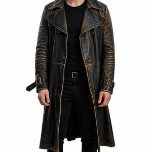 May include: A long, distressed black leather trench coat featuring a wide lapel, double-breasted button closure, and adjustable buckled straps on the cuffs. The leather displays a weathered, brownish-black finish with visible seams throughout.