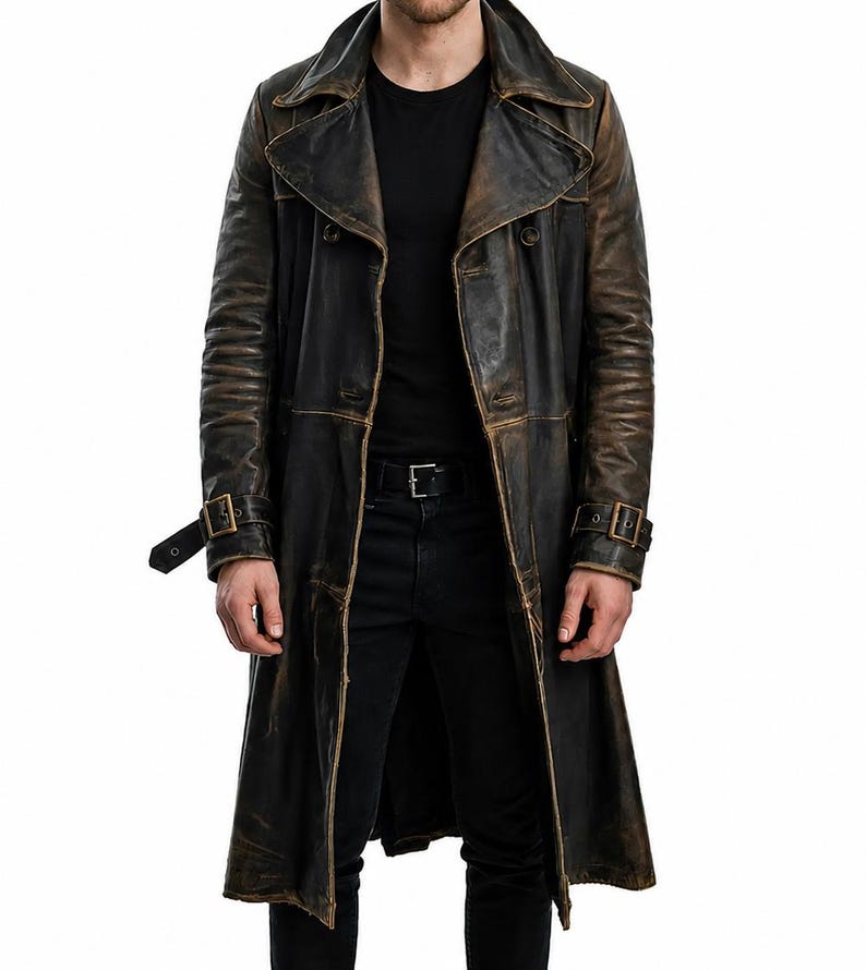 May include: A long, distressed black leather trench coat featuring a wide lapel, double-breasted button closure, and adjustable buckled straps on the cuffs. The leather displays a weathered, brownish-black finish with visible seams throughout.