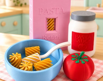 May include: A toy set featuring a pink box labeled PASTA Rotini, a white jar with a gray lid labeled PASTA SAUCE, a blue bowl containing yellow rotini pasta pieces and a white spoon, and a red tomato with a green stem, all arranged on a checkered cloth.
