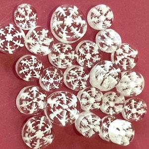 May include: A collection of clear glass round ornaments with white snowflake designs.