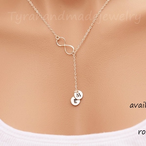 May include: A silver infinity necklace with two small charms that spell "ME". The necklace is available in silver, gold, and rose gold.