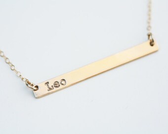Op de afbeelding: Een gouden bar ketting met de naam "Leo" erop gegraveerd.