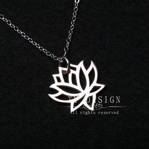 Puede incluir: Un collar de cadena de plata con un delicado colgante de flor de loto calado. El colgante está hecho de plata y tiene un diseño detallado.