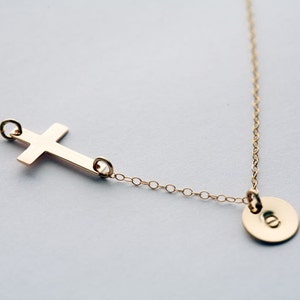 May include: A gold chain necklace with a simple cross pendant and a small round disc pendant.