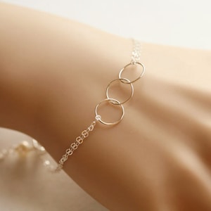 May include: A silver chain bracelet with three interconnected circles.