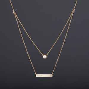 May include: Gold layered necklace with a small round clear stone pendant and a bar pendant engraved with the initials "JSP".