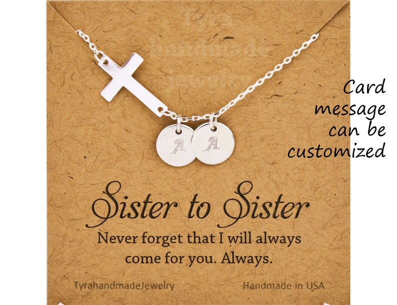 May include: Silver necklace with a cross charm and two personalized discs. The necklace comes with a card that says "Sister to Sister" and "Never forget that I will always come for you. Always."
