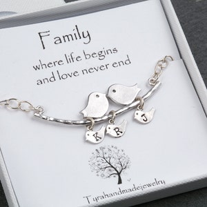 May include: Silver necklace with a branch design and three birds with initial charms. The necklace is in a white box with the text "Family where life begins and love never end".