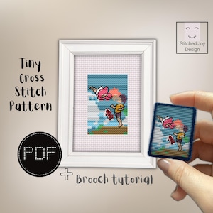May include: A cross stitch pattern featuring a person in a yellow shirt and a person in a pink outfit swimming in blue water. The design is displayed in a white frame and as a small rectangular brooch. Text includes Tiny Cross Stitch Pattern, PDF, Brooch tutorial, and Stitched Joy Design.