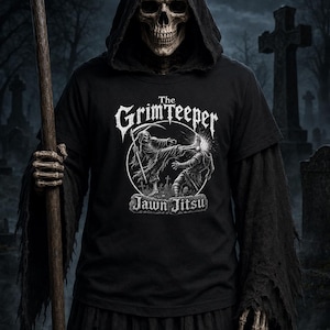 Puede incluir: Una camiseta negra con un estampado gráfico blanco de un esqueleto realizando una patada de artes marciales a otra figura. El texto dice The GrimTeeper y Jawn Jitsu. El diseño está centrado en el pecho de la prenda, usada por un esqueleto.