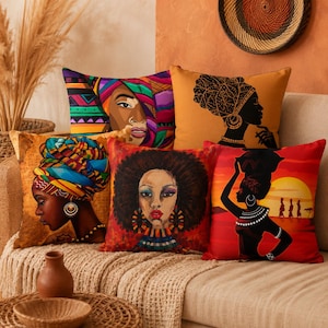 May include: A collection of five square throw pillows featuring artistic illustrations of Black individuals. The designs include vibrant headwraps, intricate jewelry, and sunset landscapes in warm tones of orange, red, yellow, and deep brown.