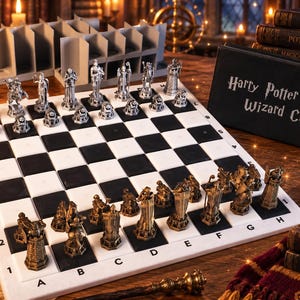 May include: A Harry Potter Wizard Chess set featuring a black and white checkered board with alphanumeric coordinates. The set includes metallic silver and bronze-toned sculpted character chess pieces, a black storage box, and a stack of books.