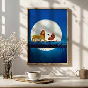 Op de afbeelding: Een ingelijste muurkunstprint met een gouden leeuw, een bruin wrattenzwijn en een klein stokstaartje die in een rij over een donkere boomstam lopen tegen een grote, heldere witte volle maan in een diepblauwe nachtelijke lucht.