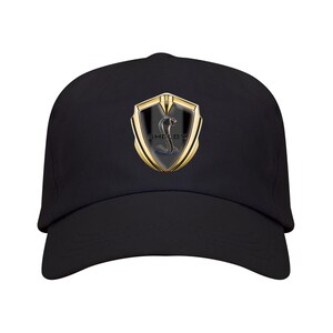 Peut inclure: Une casquette de baseball noire arborant un emblème central avec une bordure en forme de bouclier doré et un centre noir. L'emblème présente un graphique de serpent cobra argenté et le texte SHELBY en lettres noires. Visière courbée.