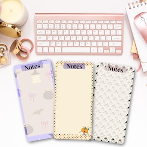 May include: Three rectangular notepad sheets with the word Notes printed at the top. The left sheet is light purple with ghosts, cauldrons, and bows. The center sheet is cream with a dotted border and a small pumpkin. The right sheet has a repeating pattern of ghosts and hats.