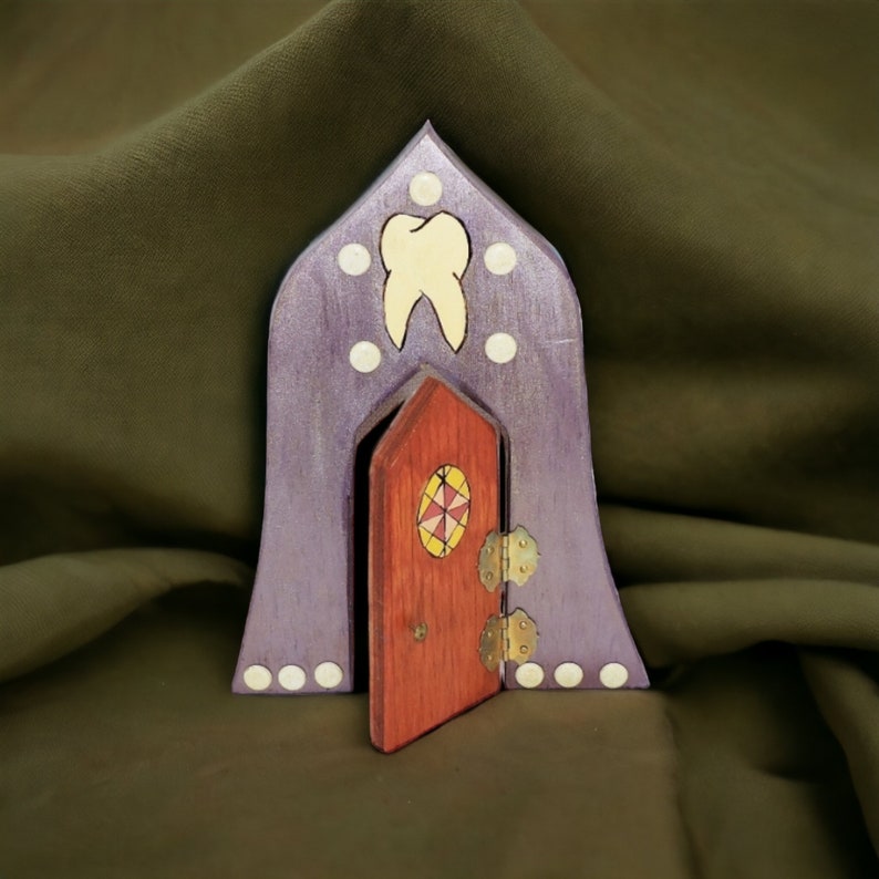 May include: A purple wooden fairy house with a white tooth design and a red door with a colorful stained glass window.