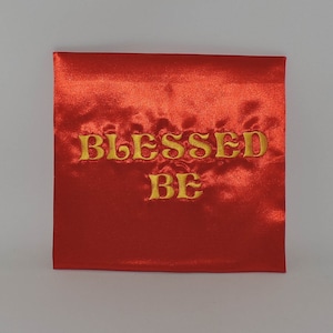 May include: Red satin pillow with the words "Blessed Be" embroidered in gold.