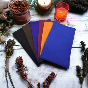 May include: A set of seven fabric swatches in various colors, including black, brown, dark blue, burgundy, orange, and light blue. The swatches are arranged in a fan shape on a white wooden surface.