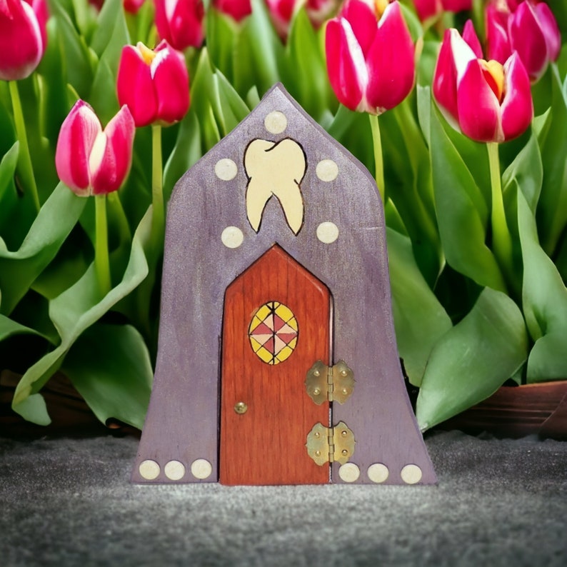 May include: A purple wooden fairy house with a red door and a tooth design. The house is surrounded by pink tulips.
