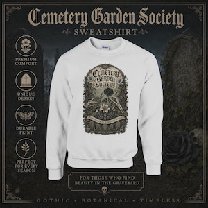 May include: A white crewneck sweatshirt featuring a central graphic with the text Cemetery Garden Society. The illustration depicts skeletal hands holding a black rose and a white lily, surrounded by ornate botanical details and tombstones.