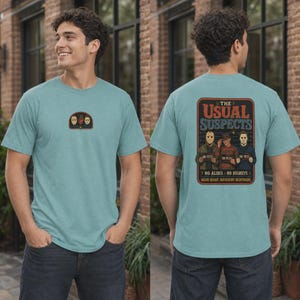 Puede incluir: Una camiseta azul claro con un peque&ntilde;o gr&aacute;fico en el pecho y un gr&aacute;fico grande en la espalda. El dise&ntilde;o de la espalda muestra tres personajes de pel&iacute;culas de terror con el texto THE USUAL SUSPECTS, NO ALIBIS, NO REGRETS, SAME NIGHT, DIFFERENT NIGHTMARE.