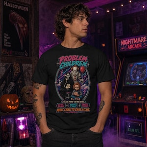 Puede incluir: Una camiseta negra con un estampado gr&aacute;fico de tres personajes de pel&iacute;culas de terror, el texto "PROBLEM CHILDREN" en la parte superior y "CLASS PHOTO - DO NOT RETAKE" debajo. El texto inferior dice "CLASS CLOWN", "BIGGEST CALLER", "SHORTEST TEMPER" y "MOST LIKELY TO CAUSE A SCENE."