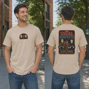 Puede incluir: Una camiseta beige de manga corta con un peque&ntilde;o gr&aacute;fico en el pecho y un gr&aacute;fico grande en la espalda. El dise&ntilde;o de la espalda muestra a tres personajes de pel&iacute;culas de terror como sospechosos con el texto "THE USUAL SUSPECTS" y "NO ALIBIS NO REGRETS."