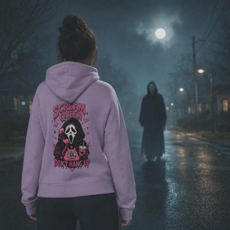 May include: A light purple hooded sweatshirt featuring a graphic on the back. The design includes a masked figure holding a pink telephone, a pink rotary phone, and a drink cup, with the text "SCREAM QUEEN" and "DON'T HANG UP" in pink.