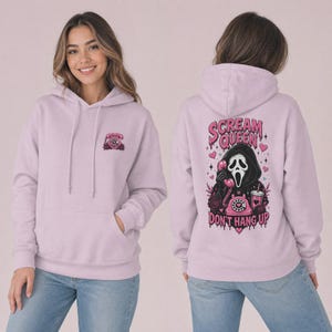 May include: A light purple hooded sweatshirt featuring a small pink rotary phone graphic on the front left chest. The back displays a large graphic of a masked figure holding a pink rotary phone with the text Scream Queen Don't Hang Up.