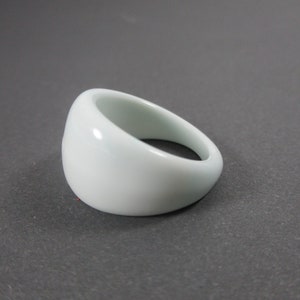 May include: A white ceramic ring with a rounded, smooth surface.