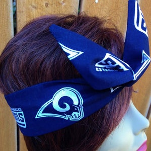 May include: A blue bandana with a white Los Angeles Rams logo and the words "Los Angeles Rams" printed on it. The bandana is tied around a person's head.