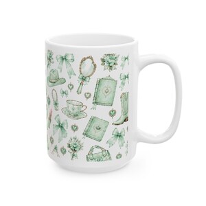 May include: A white ceramic mug featuring a repeating pattern of light green illustrations including bows, a hand mirror, a cowboy hat, a teacup and saucer, a book, a boot, a handbag, and floral bouquets arranged across the exterior surface.