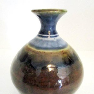 May include: A small, round, brown ceramic vase with a blue and green glaze. The vase has a narrow neck and a wide base.