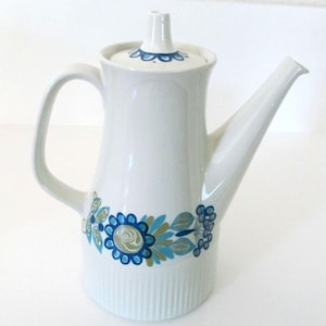 May include: White ceramic coffee pot with a blue and green floral design. The pot has a lid and a spout.