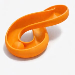 May include: A bright orange, continuous, curved track or channel forming a looped, figure-eight shape. A small, matching orange sphere rests within the smooth, concave groove of the track, which features a seamless, fluid design throughout.