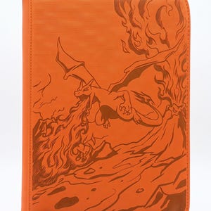 May include: An orange zipped binder featuring a dark orange line art illustration of a dragon-like creature breathing fire near a volcano. The textured cover displays the creature with wings spread, surrounded by flames and rocky terrain.