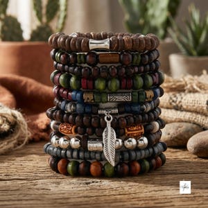 May include: A stack of ten beaded bracelets featuring various materials including dark brown wood, green, blue, and red painted beads, metallic silver spacers, and a central silver-toned feather charm hanging from the middle of the bracelet stack.
