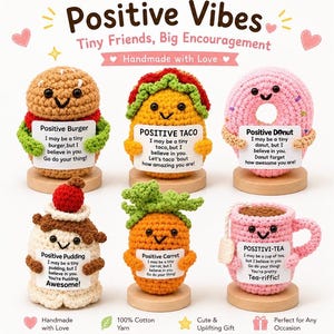 May include: Six crocheted figures on wooden bases: a burger, taco, donut, pudding, carrot, and tea cup. Each figure holds a white card with text. The burger says Positive Burger, the taco says Positive Taco, the donut says Positive Donut, the pudding says Positive Pudding, the carrot says Positive Carrot, and the tea cup says Positivi-Tea.