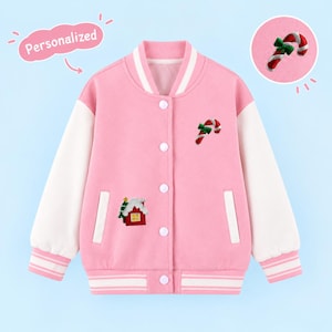 May include: A pink and white varsity jacket featuring a snap-button front closure, striped ribbed cuffs, and a collar. The jacket is decorated with embroidered patches of a candy cane and a small house with a tree. The text Personalized is visible.