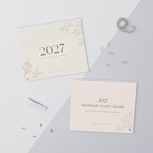 May include: Two spiral-bound 2027 calendars with cream-colored covers. One cover features the text 2027 A YEAR OF INTENTIONAL GROWTH and line art of leaves. The other cover displays 2027 Intentional Growth Calendar and leaf illustrations.