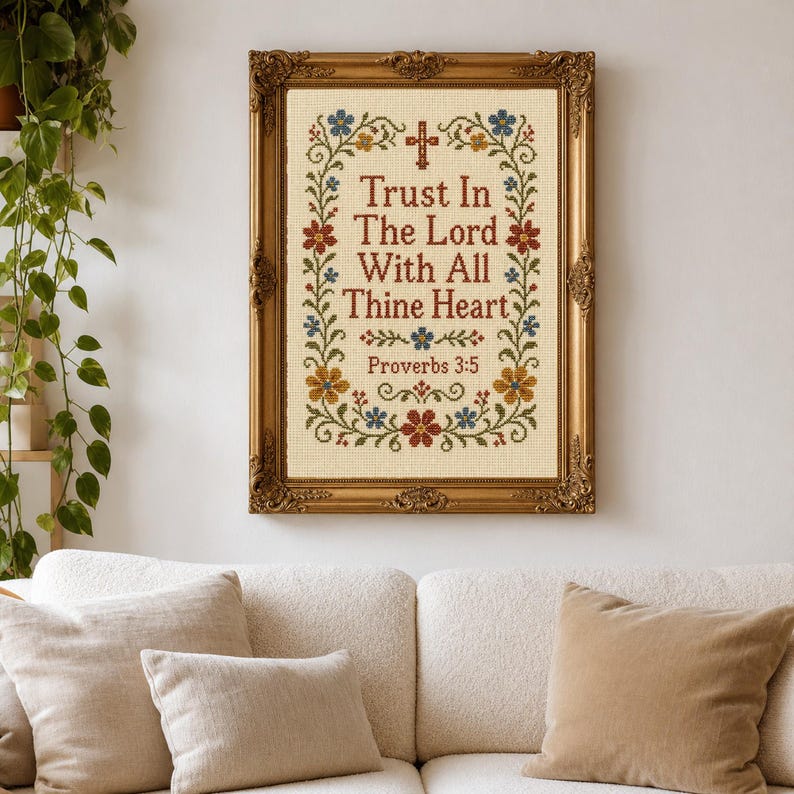 May include: A cross-stitch embroidery piece framed in an ornate gold frame. The fabric features the text "Trust In The Lord With All Thine Heart" and "Proverbs 3:5" in dark red, surrounded by a floral border with blue, red, and yellow flowers.