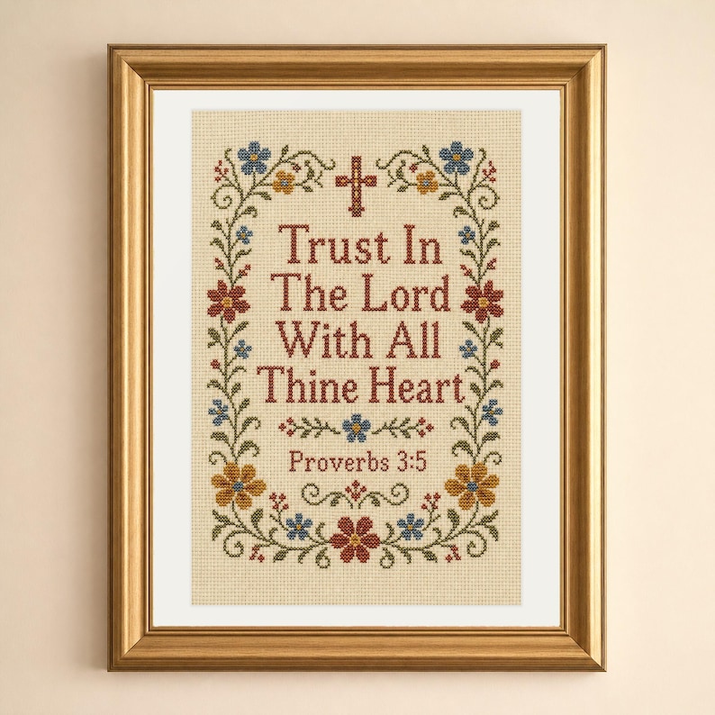 May include: A framed cross-stitch embroidery on beige fabric featuring the text Trust In The Lord With All Thine Heart Proverbs 3:5 in dark red letters. The design includes a small red cross and a floral border with blue, red, and yellow flowers.