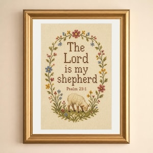 May include: A framed cross-stitch embroidery on cream fabric featuring the text The Lord is my shepherd Psalm 23:1 in brown letters. The text is surrounded by an oval floral wreath with small colorful flowers and a small sheep at the bottom.
