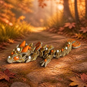 May include: A flexible, articulated lizard figurine featuring a tan body with gold-trimmed scales, bright orange accents on the head, back, and tail, and small white spherical details along its spine, resting in a low, crawling position.