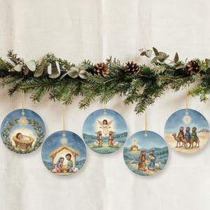 Peut inclure: Cinq ornements circulaires en céramique présentant des illustrations colorées de l'histoire de la Nativité, incluant l'enfant dans une crèche, la Sainte Famille, un ange avec des bergers, des voyageurs sur un chemin et les Rois Mages à dos de chameau.