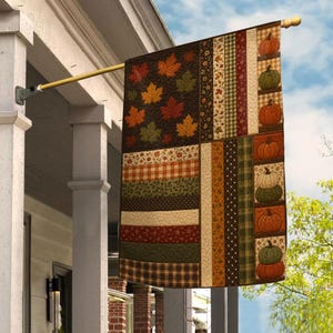 May include: A rectangular decorative flag featuring a patchwork design with autumn themes. The left side displays maple leaves in red, orange, and green on a dark background. The right side shows stacked pumpkins and vertical stripes in plaid and floral patterns.